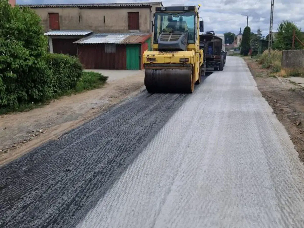 Walec drogowy ubija nową nawierzchnię. Zastanawiasz się, ile kosztuje zrobienie drogi asfaltowej?