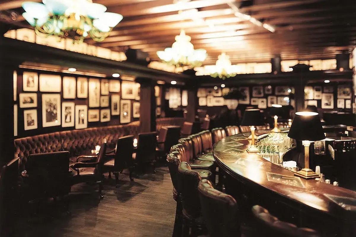 Przytulny bar w Itaewon, z rzędami skórzanych siedzeń, ozdobionymi ścianami i ciepłym oświetleniem.