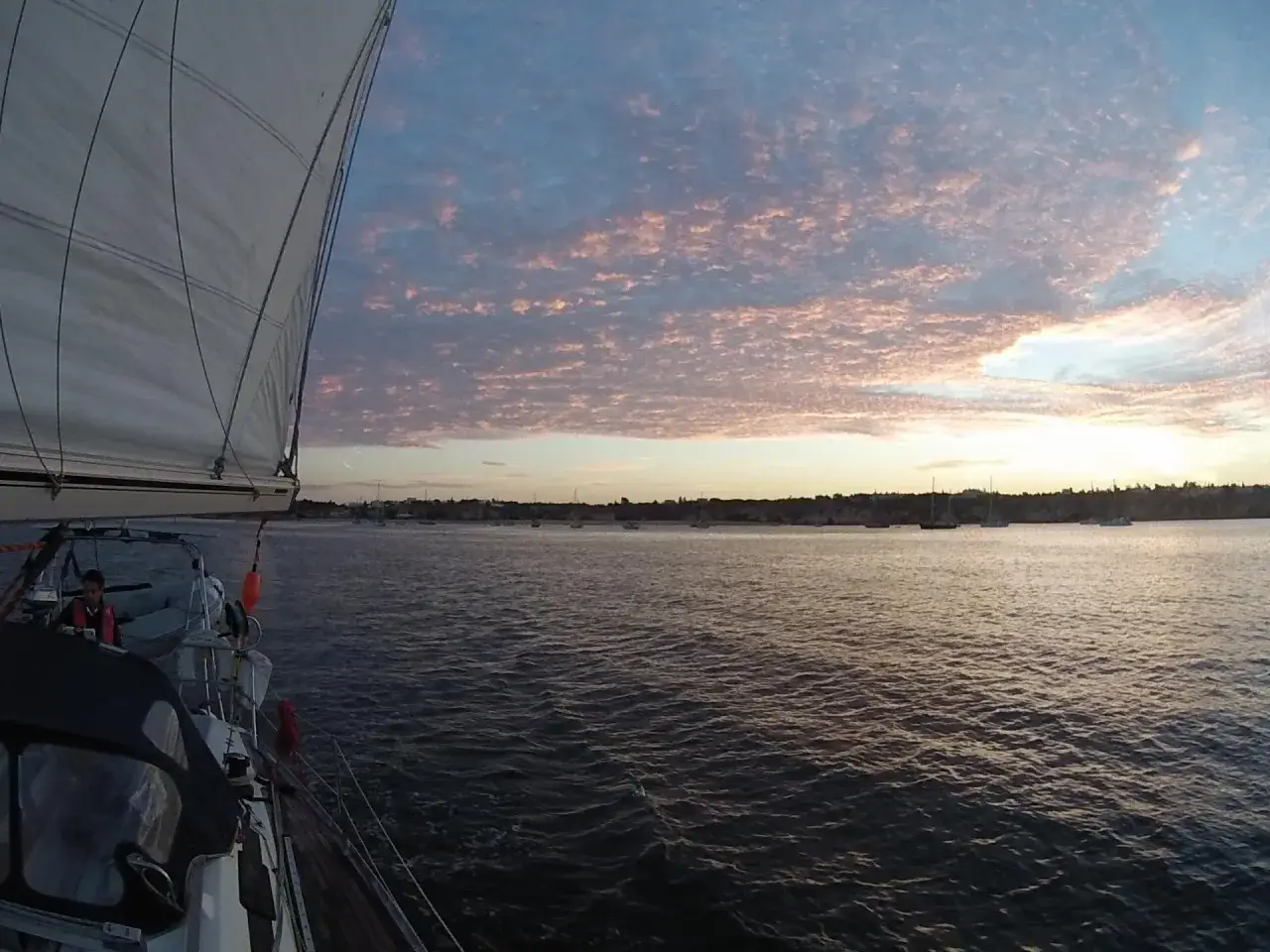 Un voilier navigue sur une mer calme sous un ciel rose et bleu. Une douce brise, un voilier love love, emporte ce rêve.