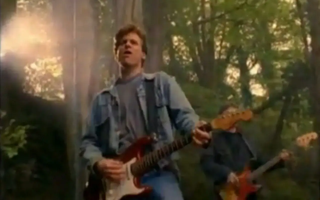 Bryan Adams gra na gitarze w lesie, jak w piosence z Robin Hooda.