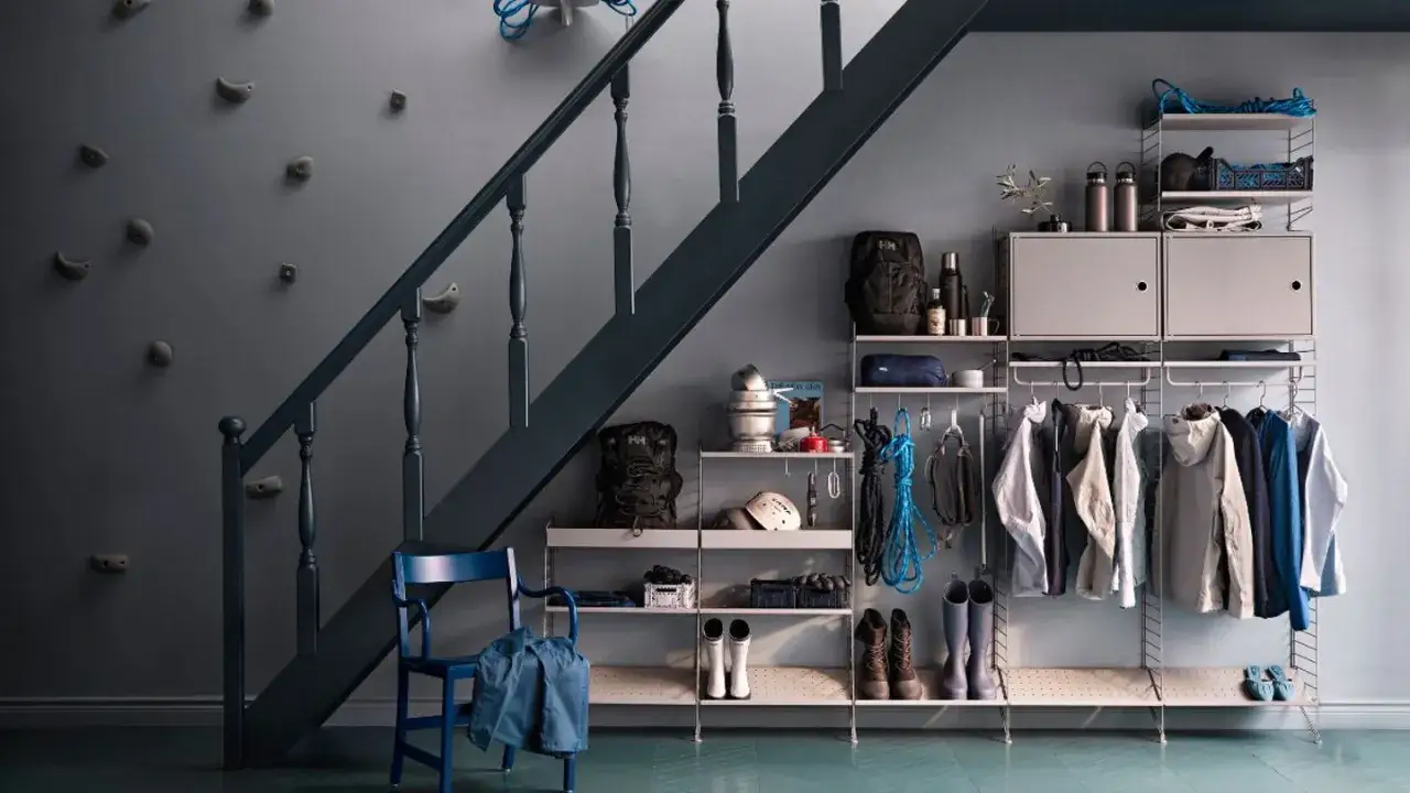 Praktische Garderobe unter der Treppe mit Klettergriffen an der Wand, Kleidung, Rucks&auml;cken und Kletterseilen.