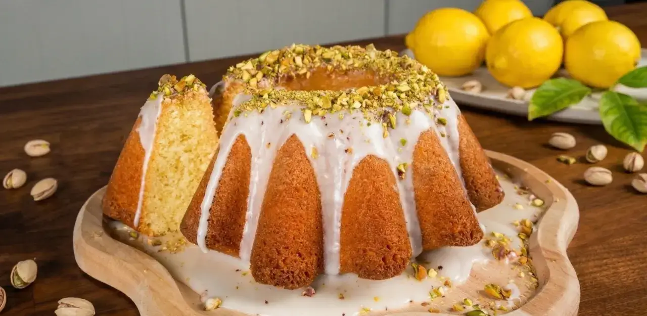 Pyszne ciasto na Wielkanoc, udekorowane lukrem i pistacjami, z kawałkiem obok. Idealne na świąteczny stół.