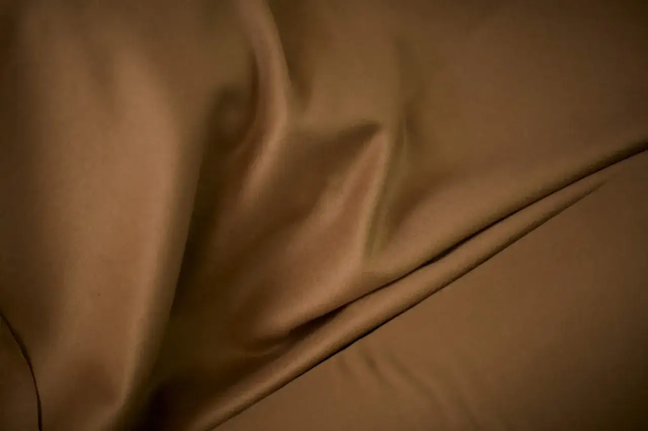 Drap&eacute; de tissu brun, doux et chaud comme du poil de chameau, &eacute;voquant le d&eacute;sert.