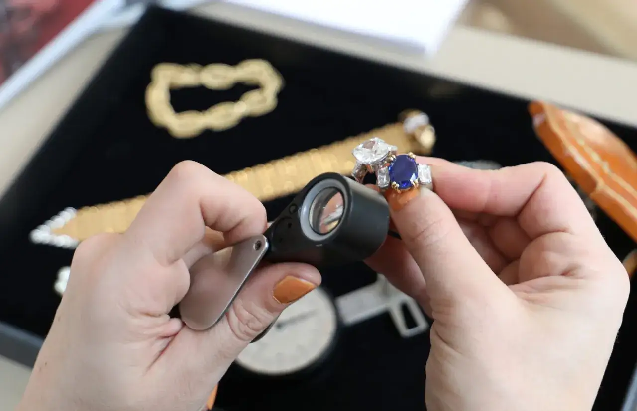 Maintenant, o&ugrave; faire expertiser des bijoux gratuitement ? Une loupe examine une bague saphir et diamant.