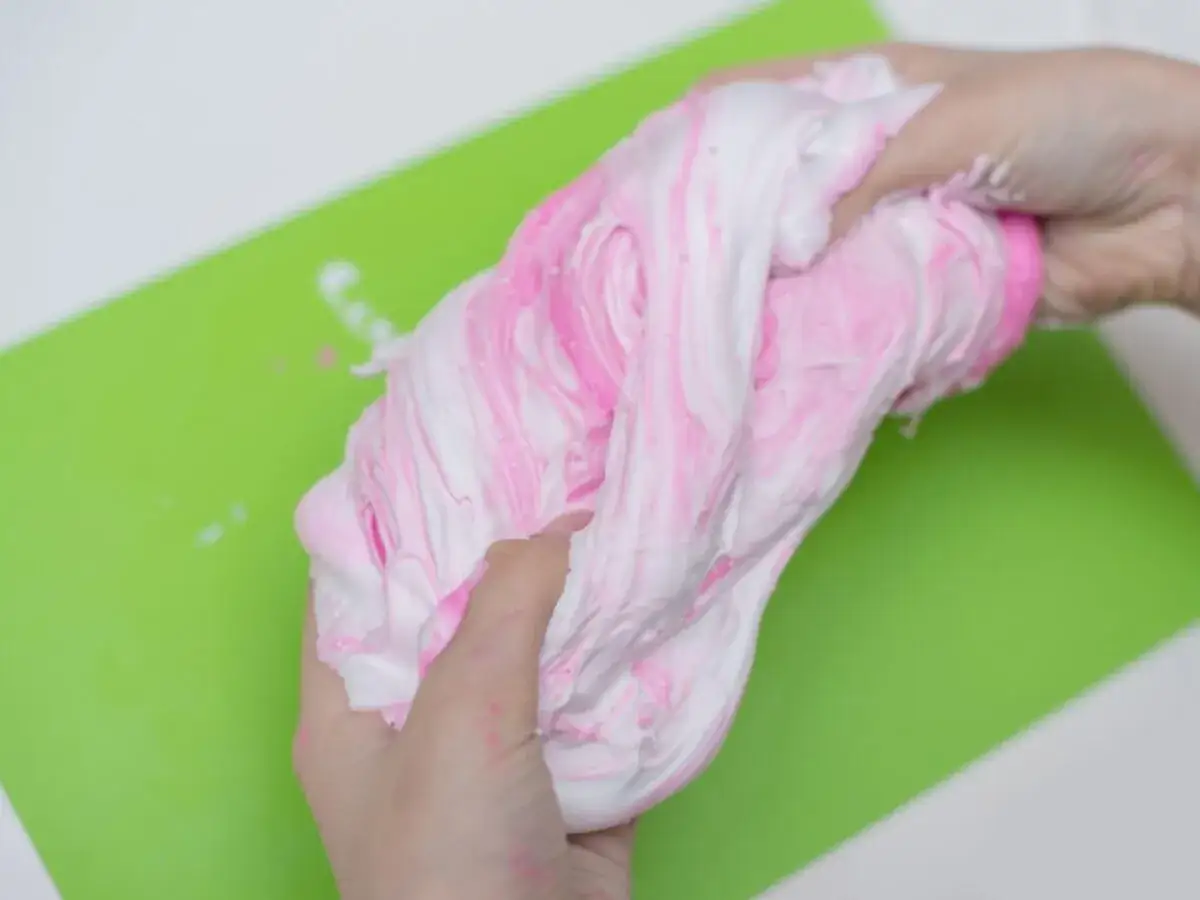 R&oacute;żowo-biały slime w rękach. Prosta instrukcja jak zrobić slime, idealna zabawa dla dzieci.