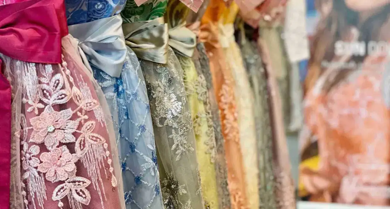 Bunte Stoffe f&uuml;r Dirndl mit Stickereien und Schleifen, von zartrosa bis leuchtend orange.
