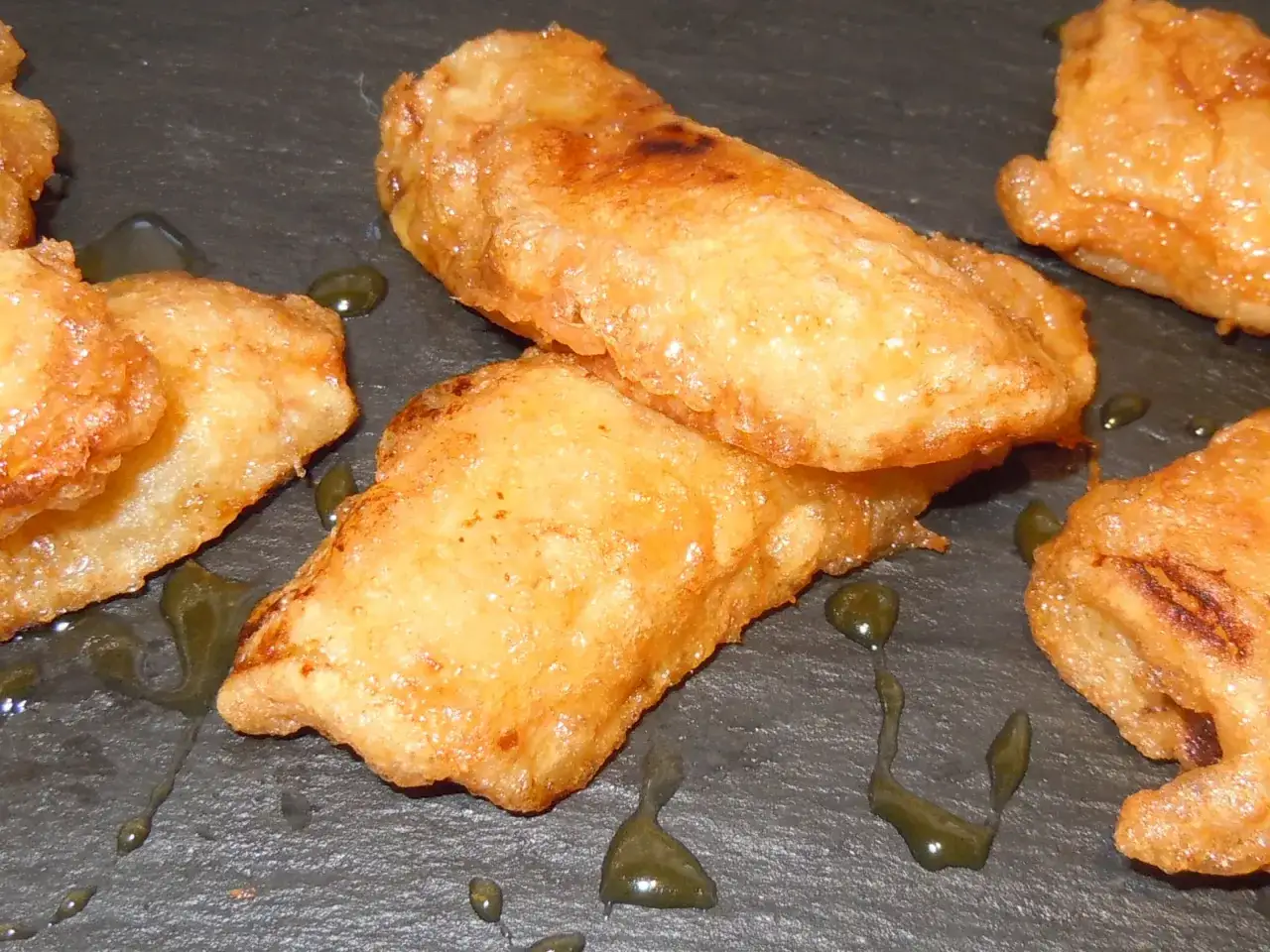 Plátanos fritos dorados y crujientes, bañados en un sirope oscuro, listos para disfrutar.