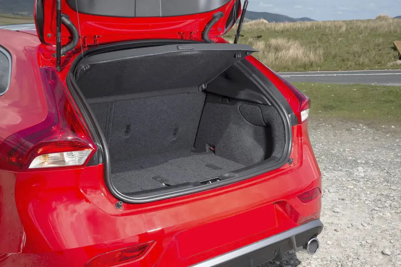 Czerwone Volvo V40 z otwartym bagażnikiem. Wnętrze jest czyste i przestronne, idealne na bagaże. Wiele osób szuka volvo v40 opinie, by sprawdzić jego praktyczność.