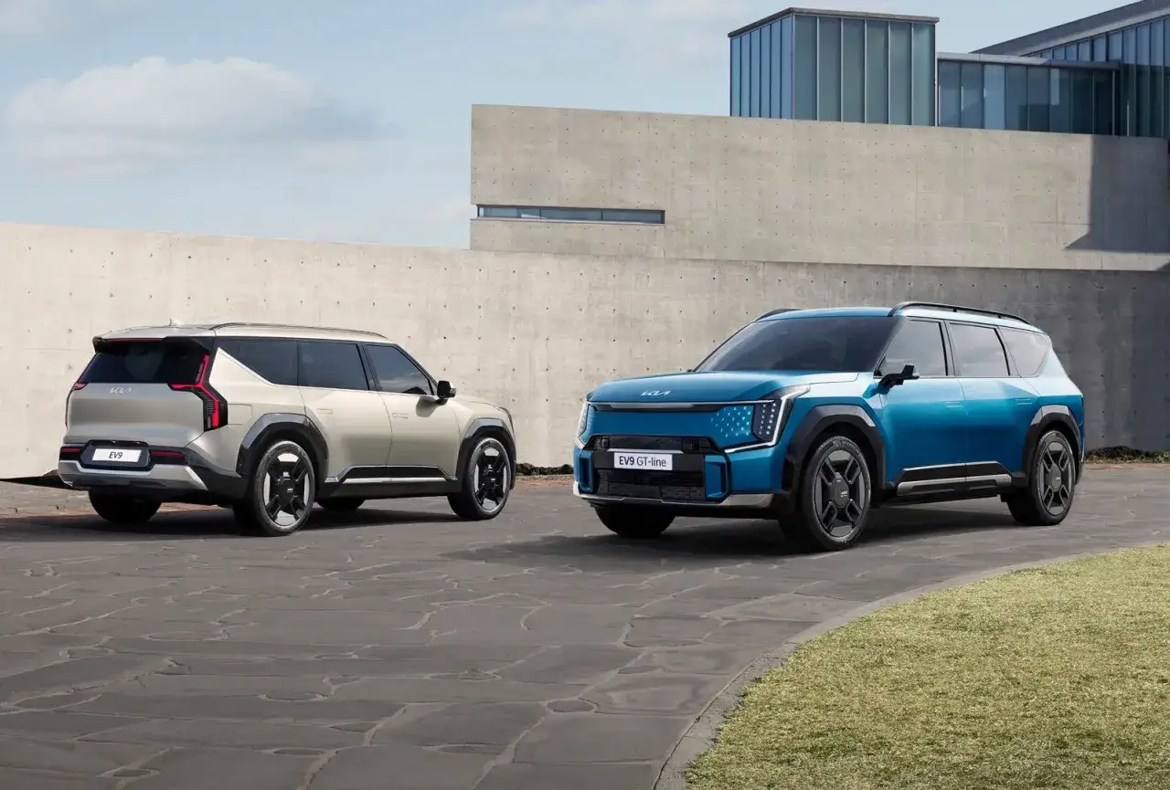 Dwa nowoczesne kia modele: niebieski EV9 GT-line i beżowy EV9, stojące przed betonowym budynkiem.