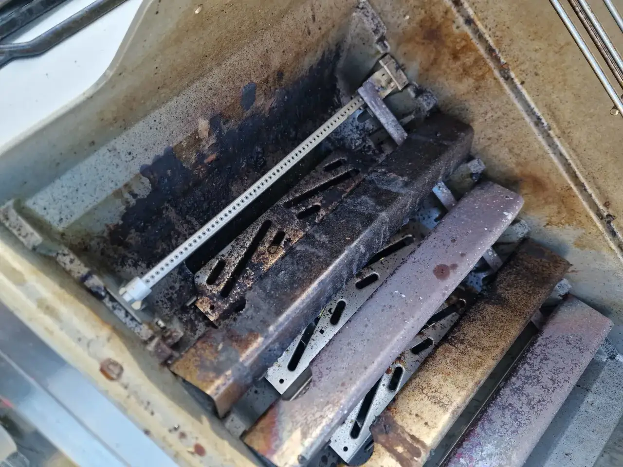 Grillens brännare är täckta av fett och smuts. Dags att rengöra grillen med avfettning för att få den skinande ren igen.