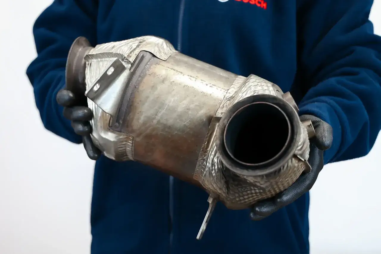 Osoba w rękawiczkach trzyma element układu wydechowego, prawdopodobnie filtr DPF (fap).