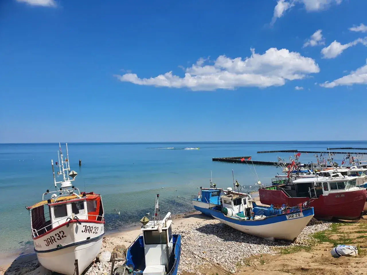 Jarosławiec kwatery prywatne blisko morza. Łodzie rybackie na plaży, spokojne morze i błękitne niebo. Idealne miejsce na wypoczynek.