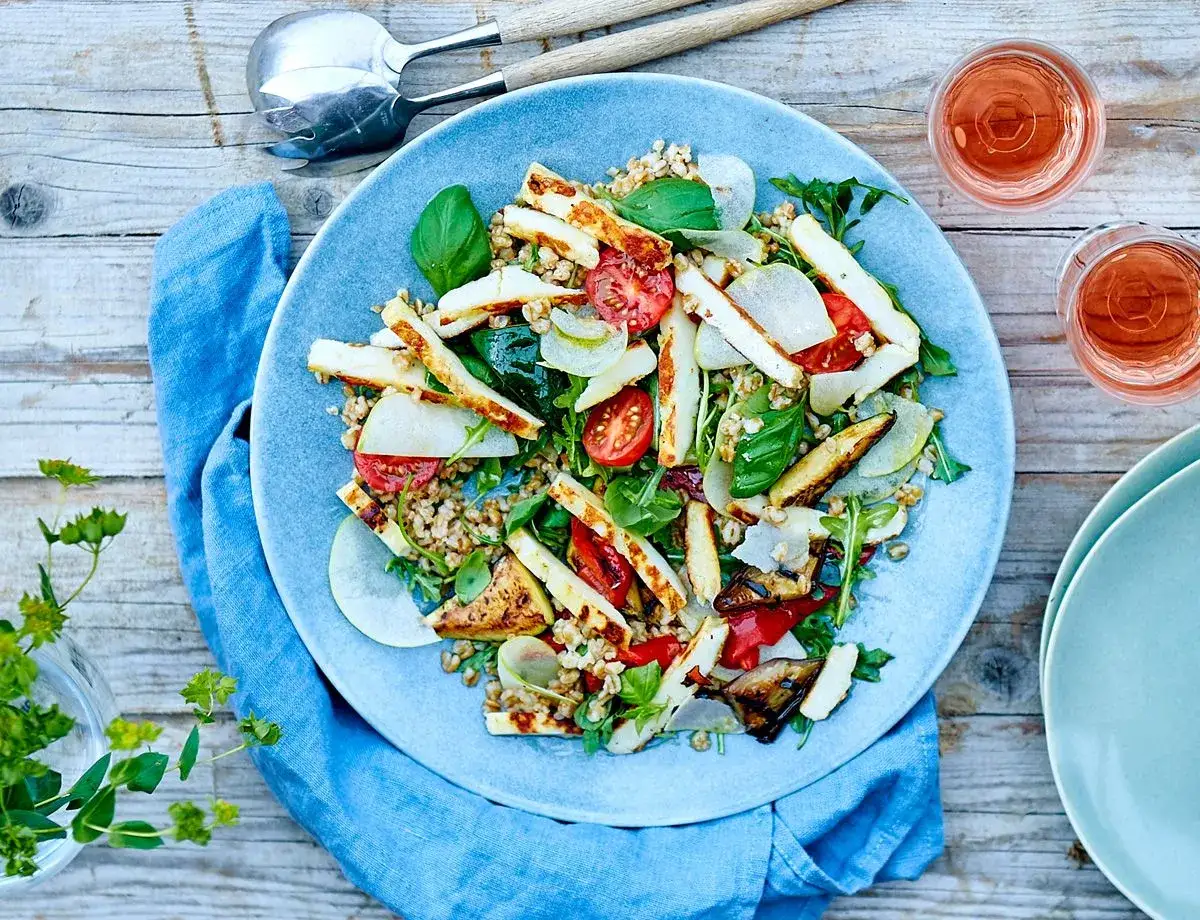 En h&auml;rlig halloumi sallad med krispiga gr&ouml;nsaker och n&ouml;tter, serverad p&aring; en bl&aring; tallrik.