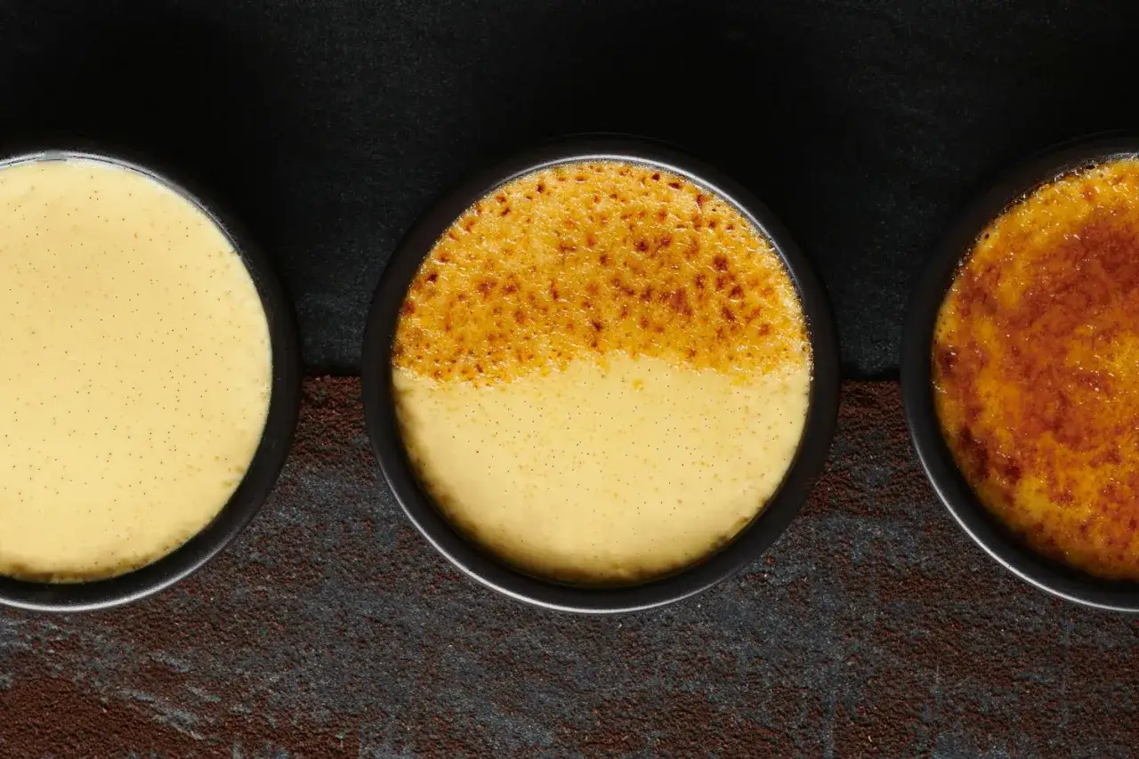 Trois ramequins de crème brûlée, dont un à la croûte caramélisée parfaite.