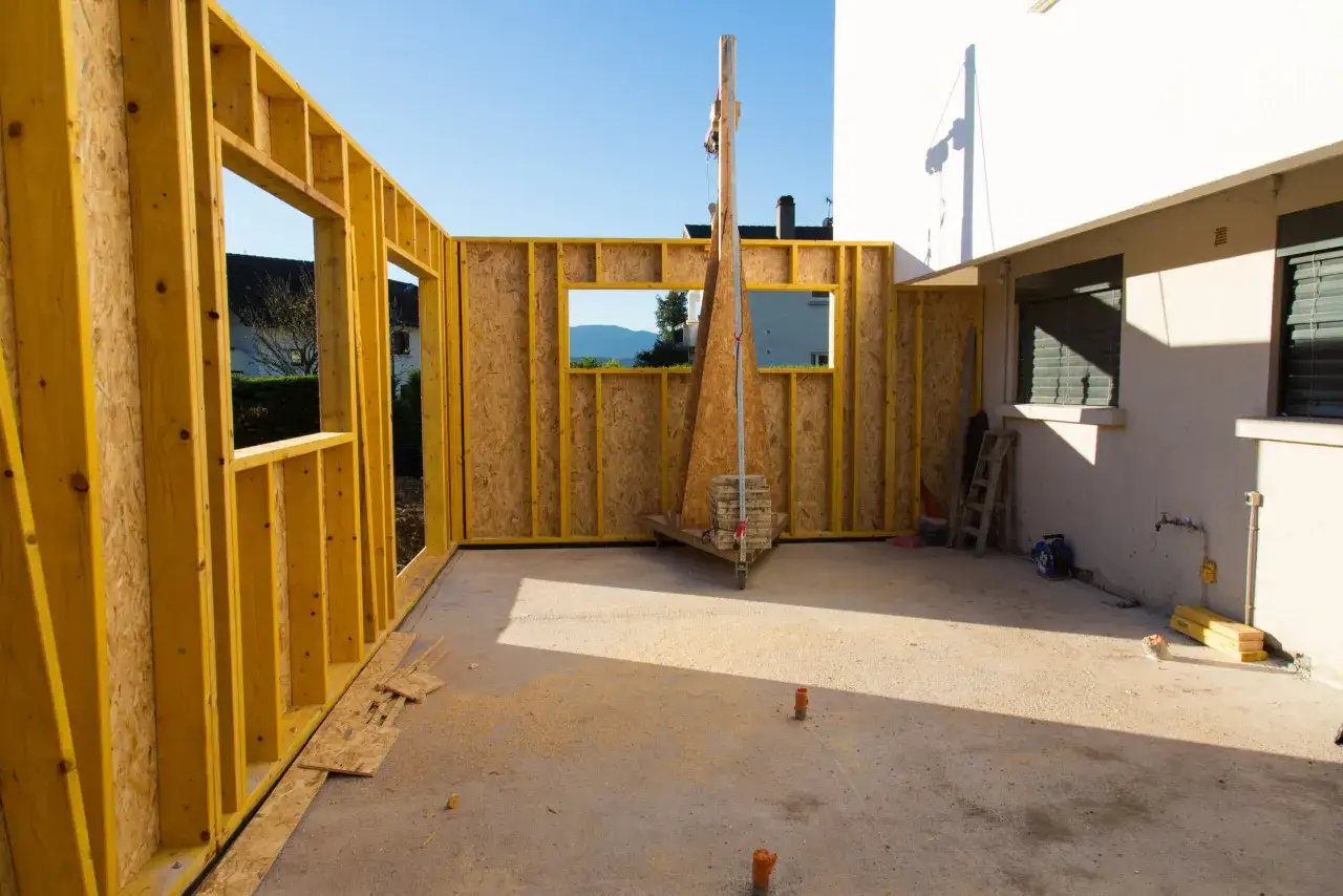 Structure en bois pour une extension de maison en cours de construction. Le soleil éclaire le chantier.