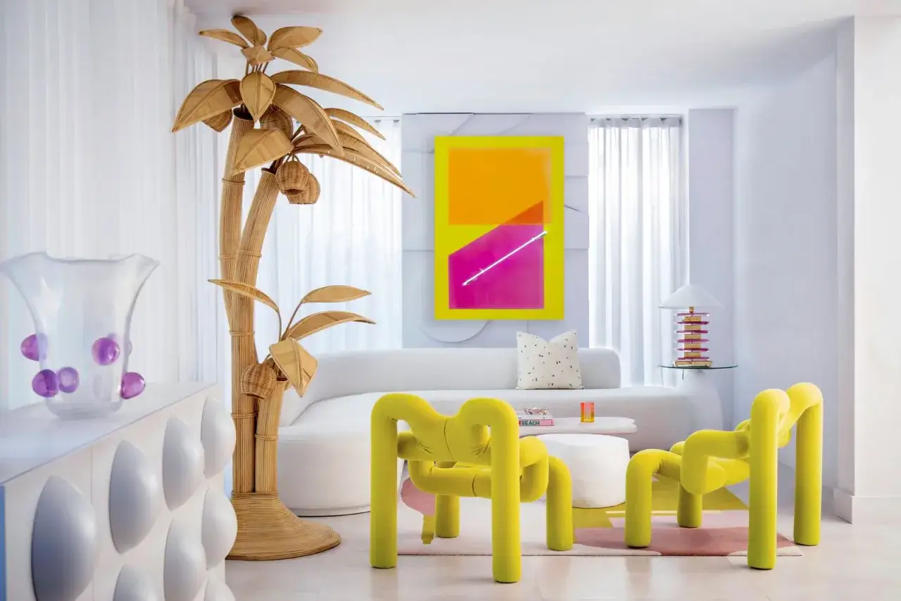 Sala de estar con vibrante arte abstracto, muebles curvos y un árbol de mimbre, todo con un audaz estilo Memphis.
