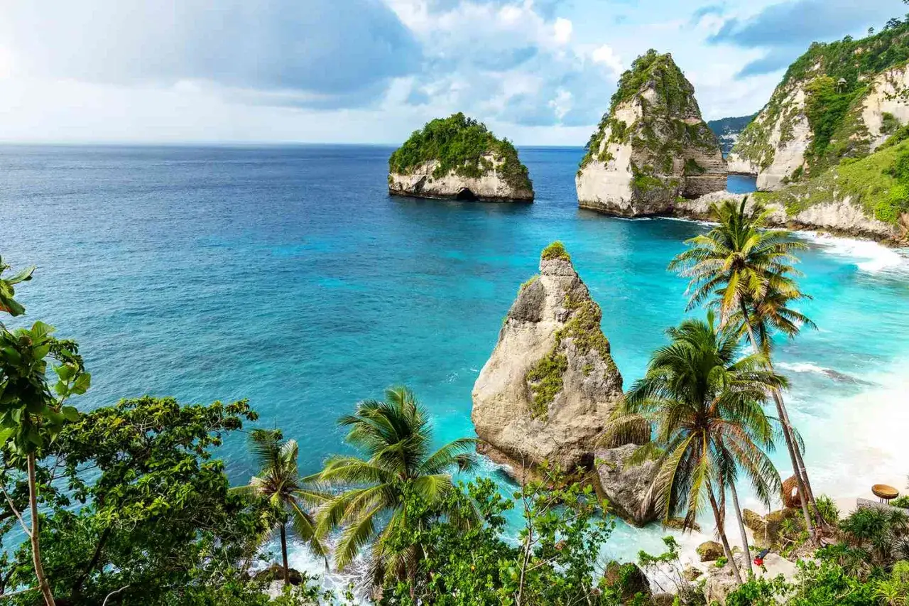 Traumhafte Felsformationen im türkisfarbenen Meer, Palmen und weißer Sandstrand. Perfekt für die beste Reisezeit Bali.