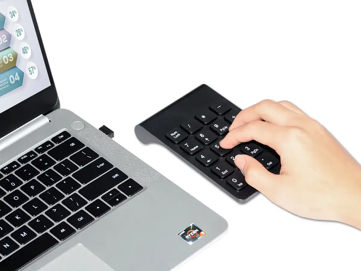 Podłącz klawiaturę do laptopa, wkładając odbiornik USB. Dłoń wpisuje liczby na klawiaturze numerycznej.