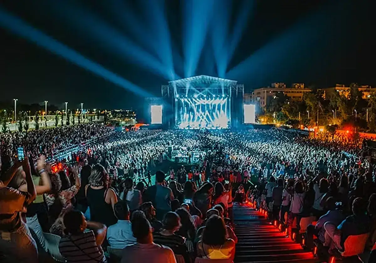 Gran multitud disfrutando de un concierto nocturno en el cabaret festival Sevilla. Luces brillantes iluminan el escenario y al público eufórico.