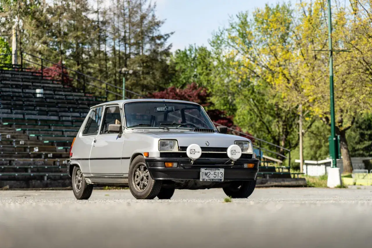 Silver Renault 5 Turbo le car med extraljus framför läktare och träd.