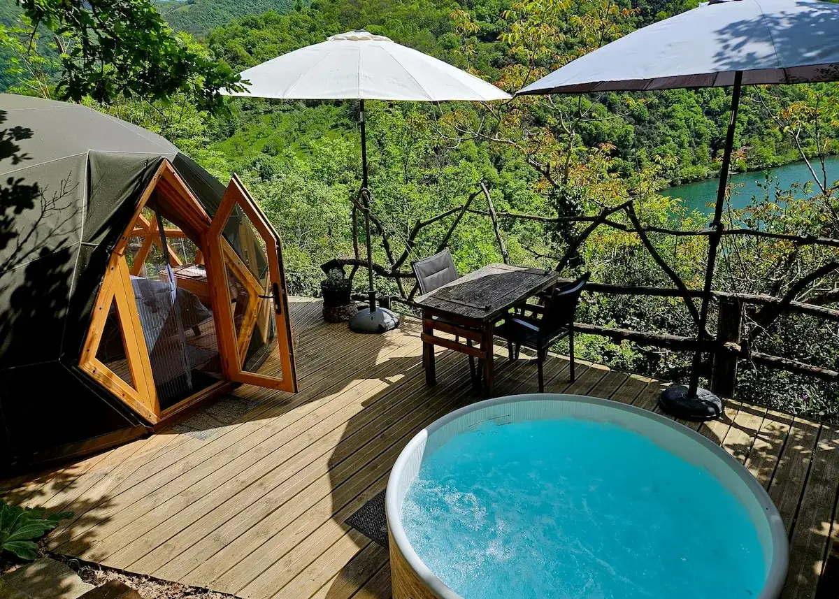 Domek w **Gorges du Tarn** z jacuzzi i widokiem na rzekę. Drewniany taras, stół z krzesłami i parasole.