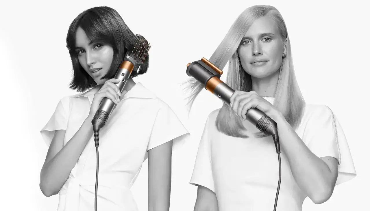Dwie kobiety stylizują włosy za pomocą Dyson Airwrap z technologią Coanda 2x. Jedna z krótkimi, druga z długimi włosami.