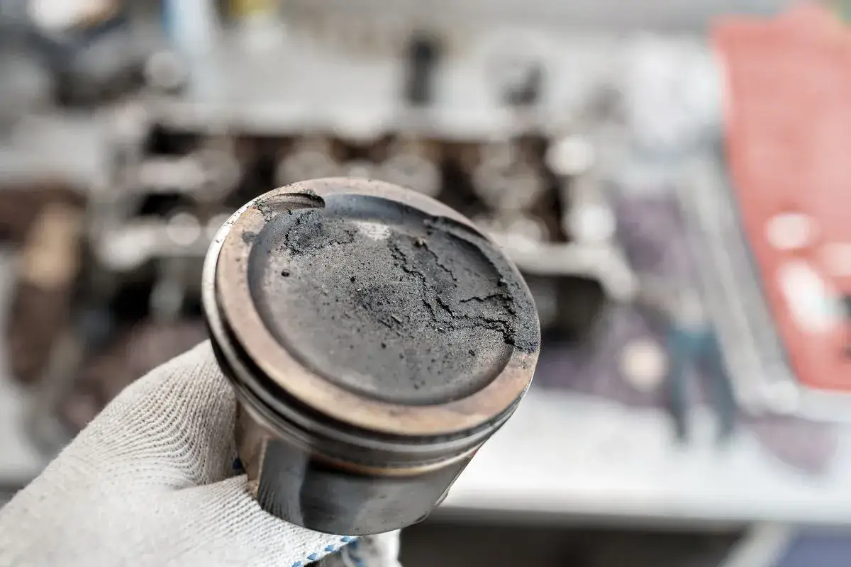 Pistón con carbonilla acumulada, un problema común que puede requerir remedios caseros para quitar la carbonilla del coche.
