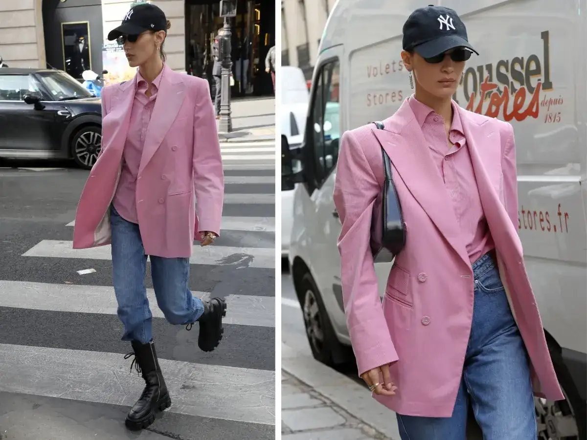 Bella Hadid w różowej marynarce i koszuli, do tego jeansy i botki. Idealna stylizacja, jeśli zastanawiasz się, jakie spodnie do różowej koszuli.