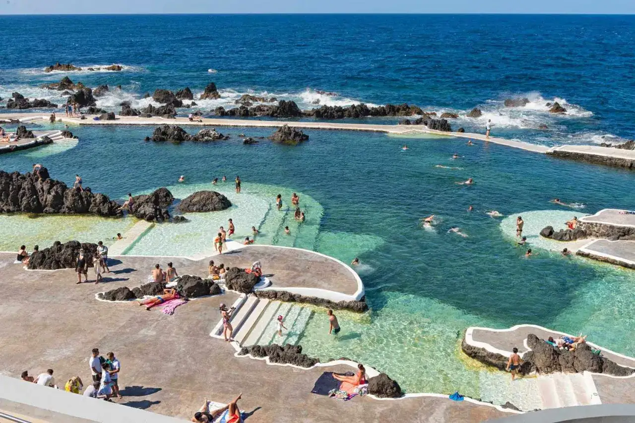 Naturschwimmbecken auf Madeira, Menschen genießen das Meer. FKK-Bereiche sind nicht explizit sichtbar, aber die entspannte Atmosphäre deutet auf Freiheit hin.