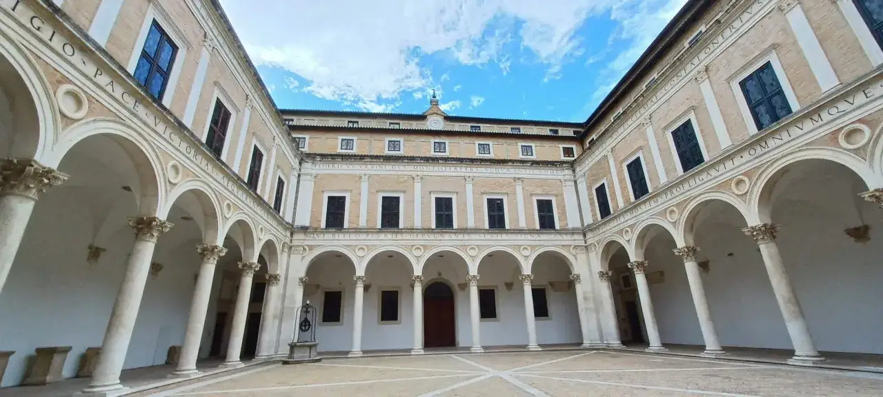 Cortile del Palazzo Ducale di Urbino, con portici ad archi sorretti da colonne corinzie. Un'antica cisterna al centro.
