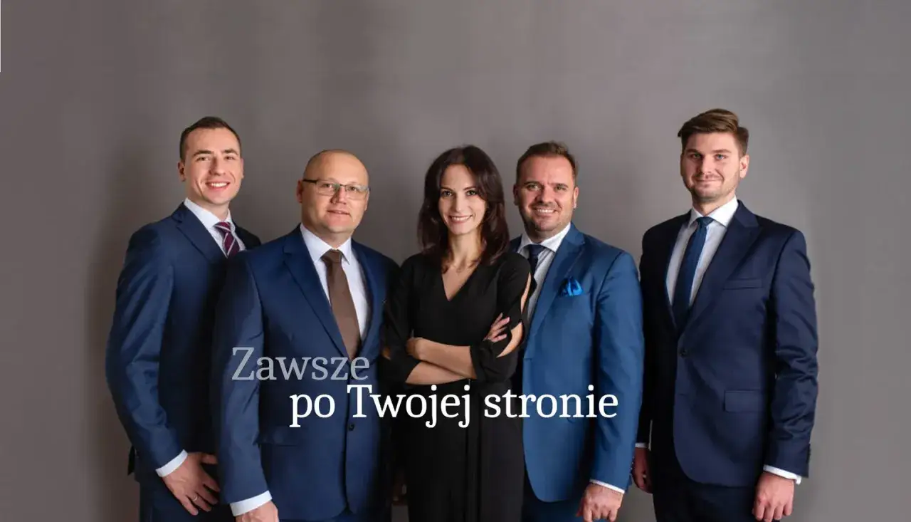 Pięć osób w garniturach i sukience pozuje do zdjęcia na szarym tle.