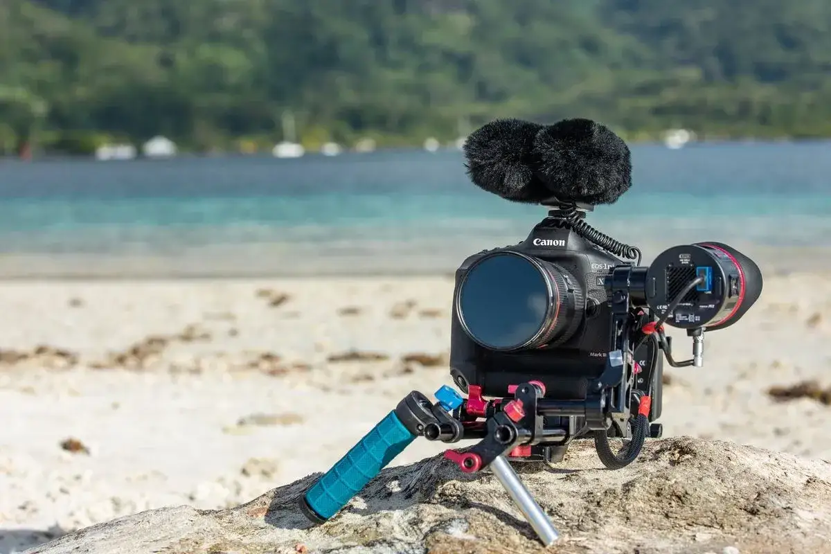 Profesjonalny zestaw filmowy z aparatem Canon 1DX Mark III na plaży, gotowy do nagrywania dźwięku i obrazu.