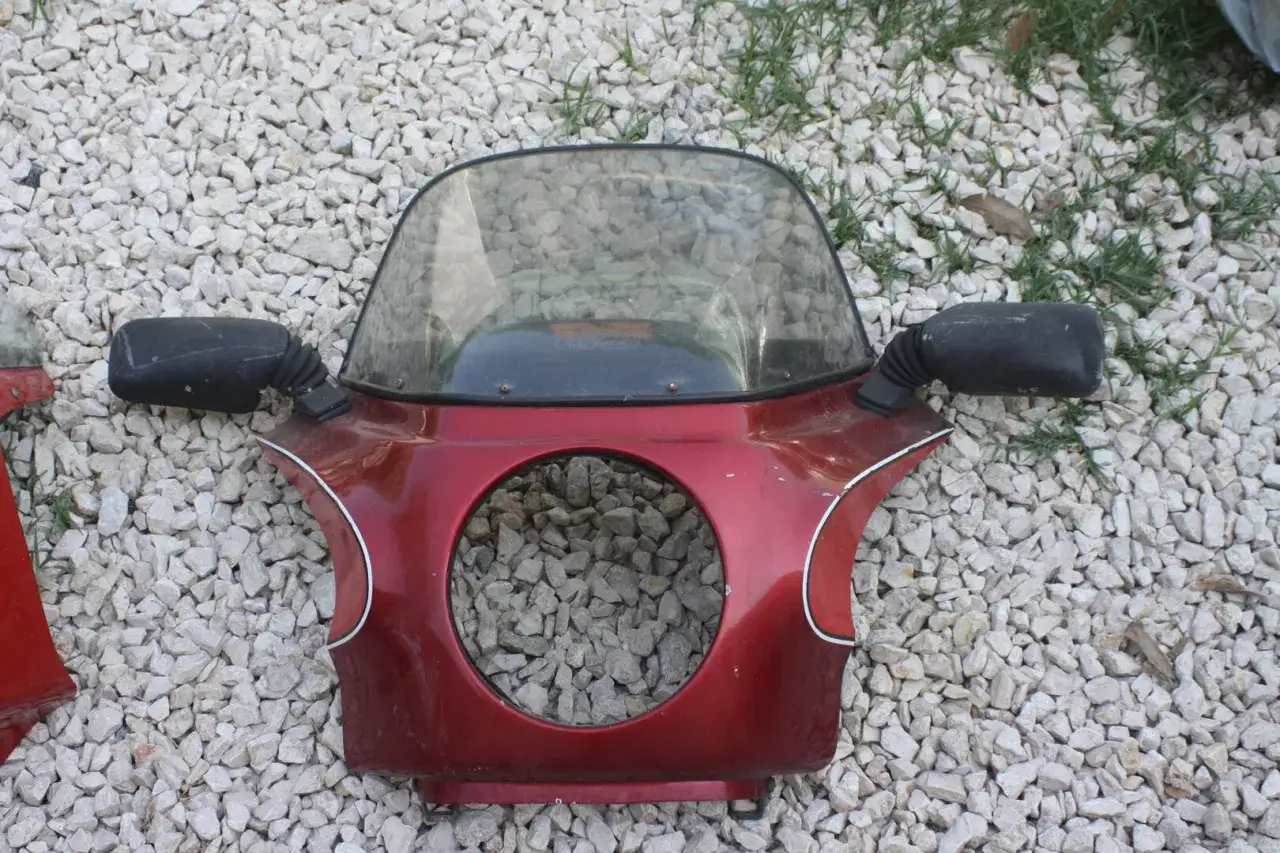 Cupolino moto rosso con specchietti neri e un foro circolare. La sigla