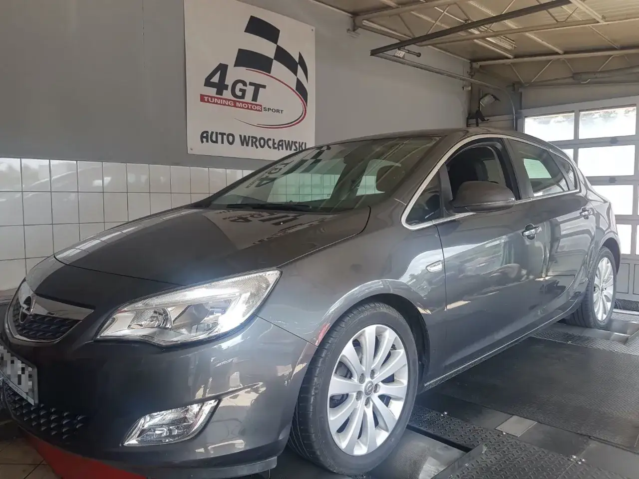 Szary Opel Astra J na hamowni. Sprawdzanie, czy moc silnika ograniczona, czy osiąga pełnię możliwości.