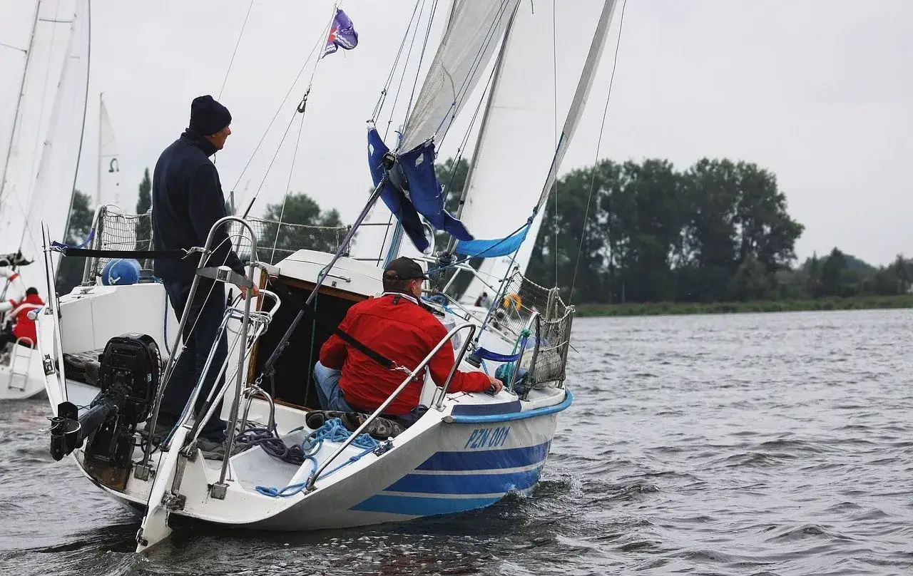 Deux hommes naviguent sur un voilier micro challenger, profitant d'une journée sur l'eau.