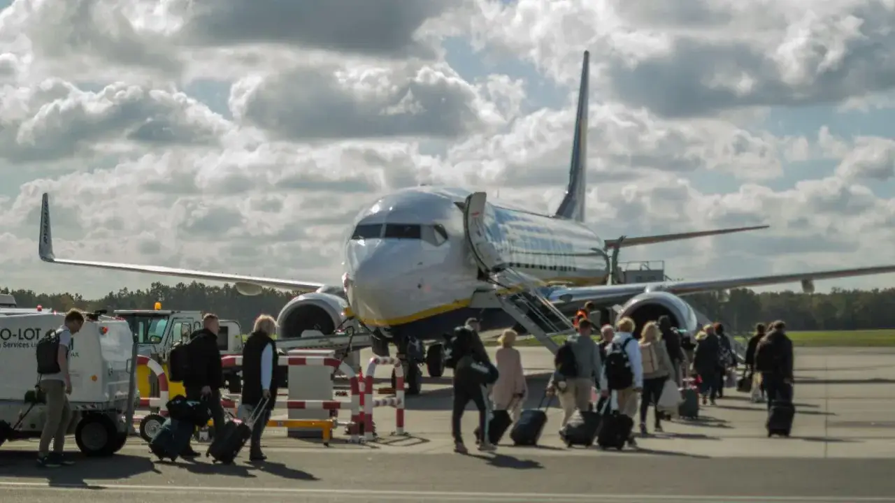 Pasażerowie z bagażami idą do samolotu Ryanair. Tak wygląda odprawa na lotnisku.