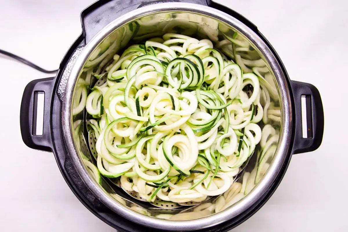 Zucchini Spaghetti in einem Schnellkochtopf. Frische, spiralf&ouml;rmige Zucchini-Nudeln warten darauf, zu einer leichten Mahlzeit verarbeitet zu werden.