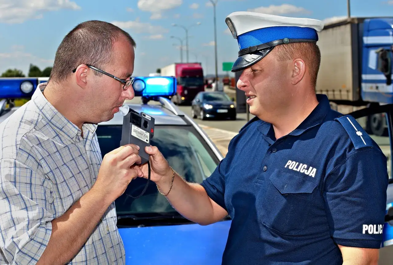 Policjant bada kierowcę alkomatem. Sytuacja, kiedy zabierają prawo jazdy, jest stresująca.