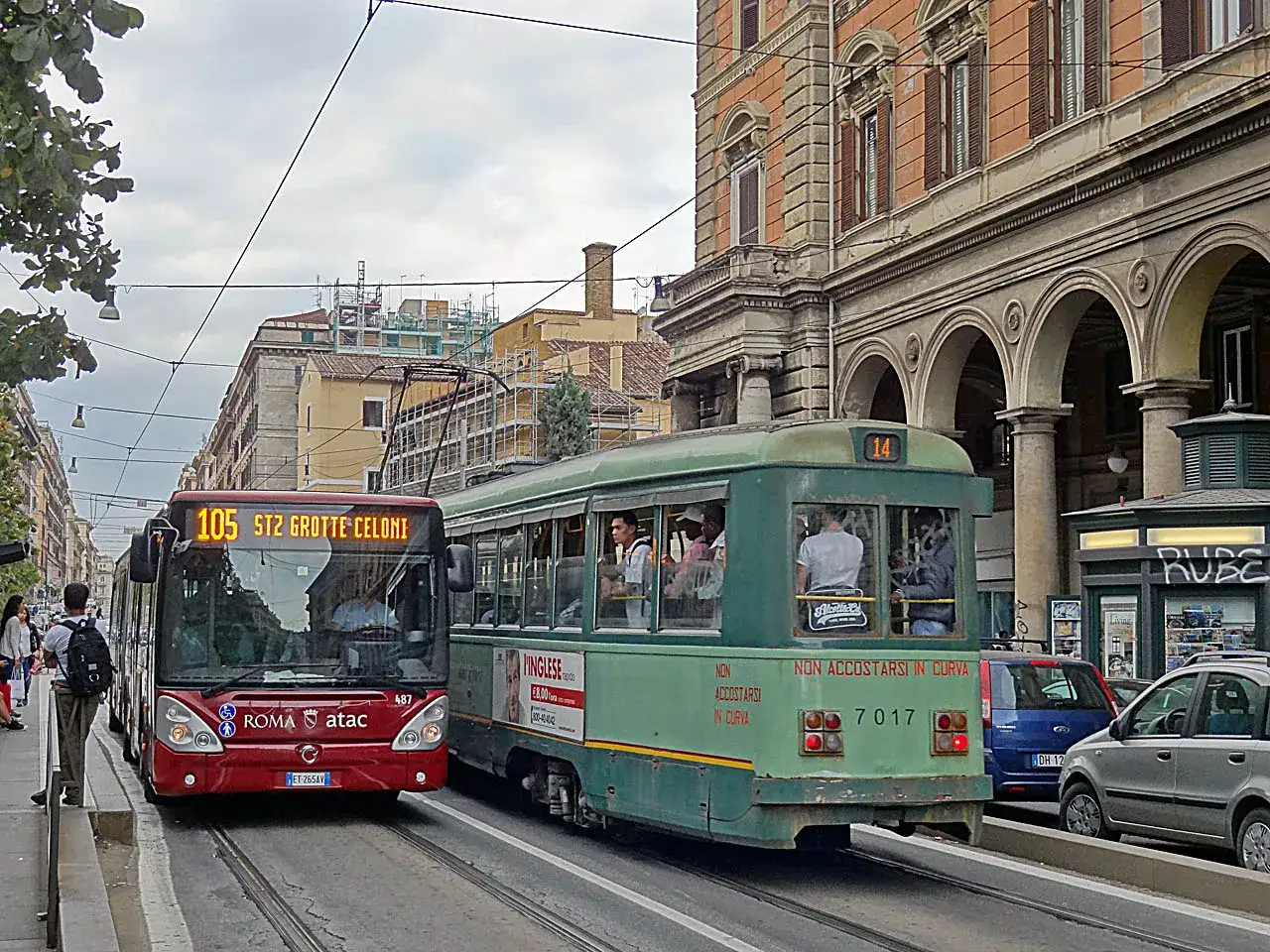 Un bus rouge ATAC et un tramway vert circulent sur les rails, offrant un aperçu du transport public à Rome.