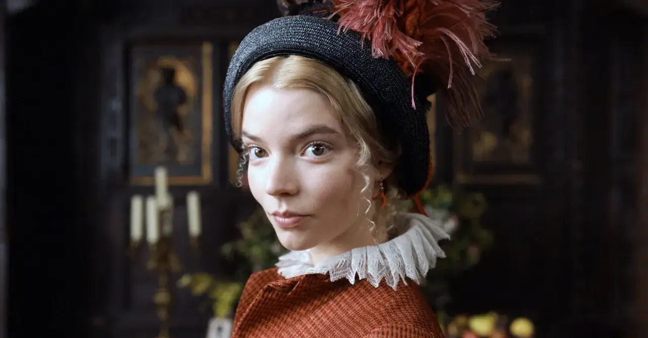 Emma (obsada) w stylowym kapeluszu z piórami i koronkowym kołnierzykiem, zamyślona.