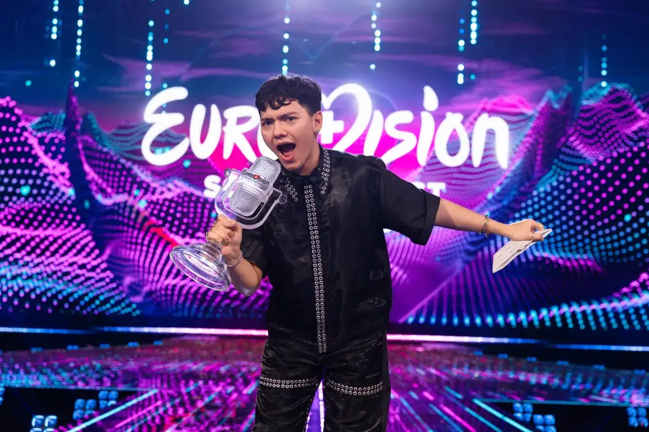 Młody artysta z Austrii triumfuje na Eurowizji, trzymając kryształowy mikrofon i wykrzykując radośnie.