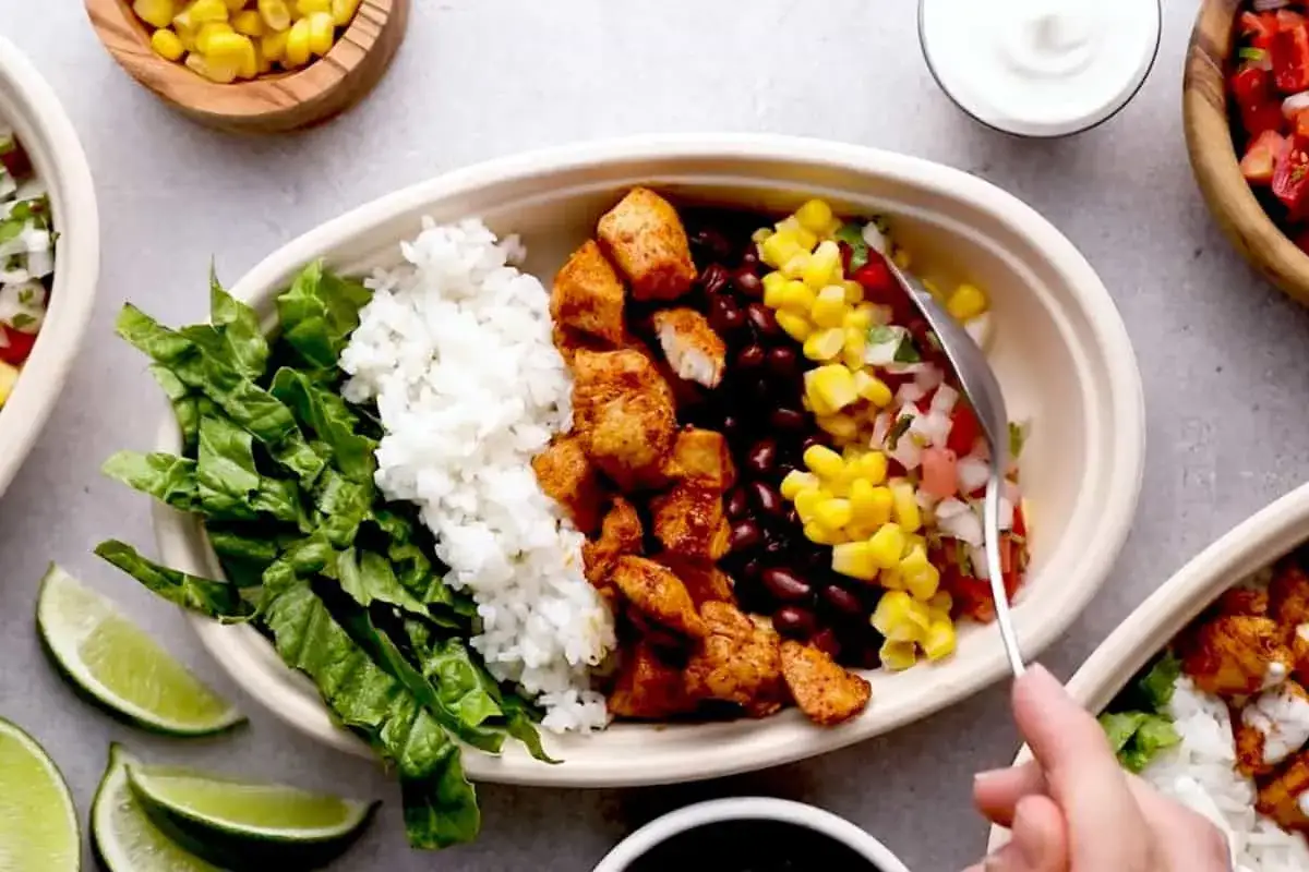 Pyszny burrito bowl z kurczakiem, ryżem, fasolą, kukurydzą i świeżą sałatą. Idealny posiłek na wynos.