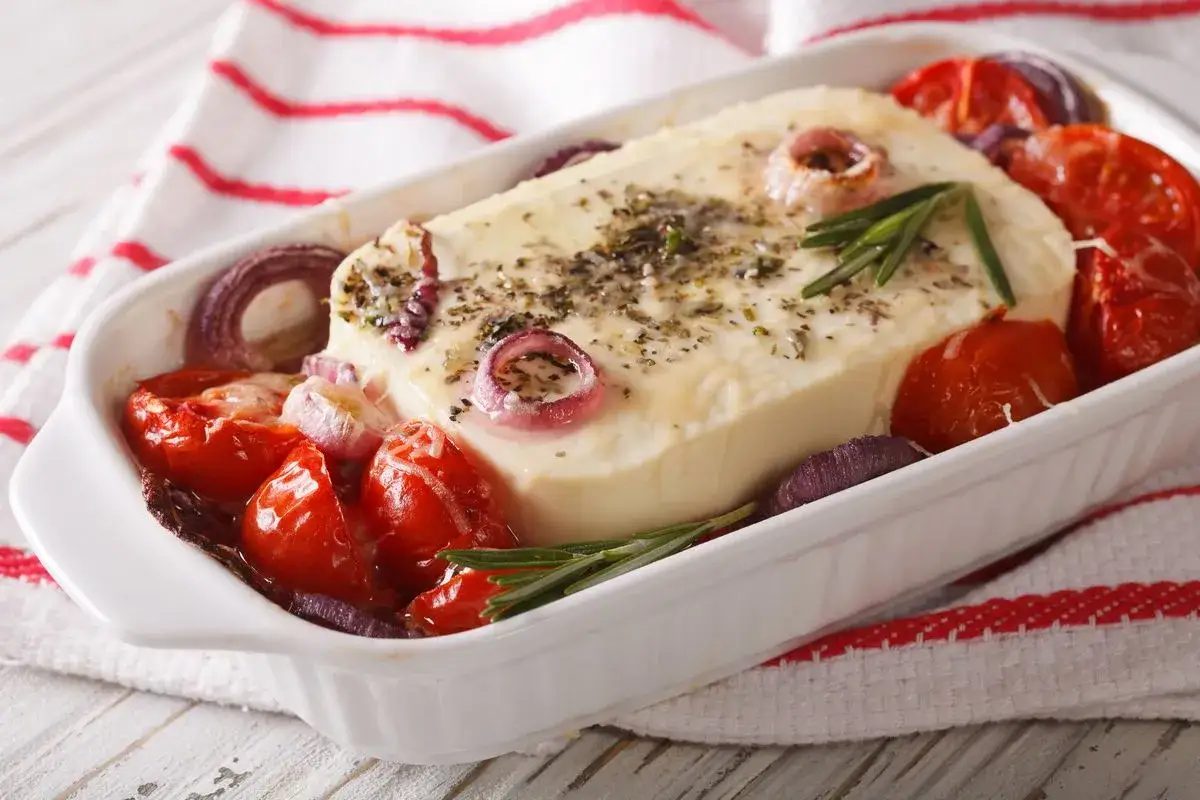 Feta al forno con pomodorini, cipolla rossa e rosmarino. Un piatto che esalta il feta sapore, pronto per essere gustato.