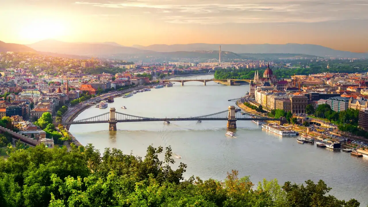 Budapest bei Sonnenuntergang: Die Donau flie&szlig;t vorbei an der Kettenbr&uuml;cke und dem Parlament. Entdecken Sie die sch&ouml;nsten Budapest Geheimtipps!
