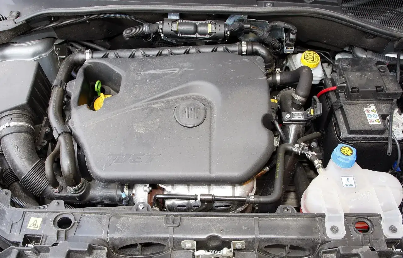 Silnik 1.4 z Fiata Grande Punto. Widoczny plastikowy kolektor, akumulator i zbiornik płynu chłodniczego.