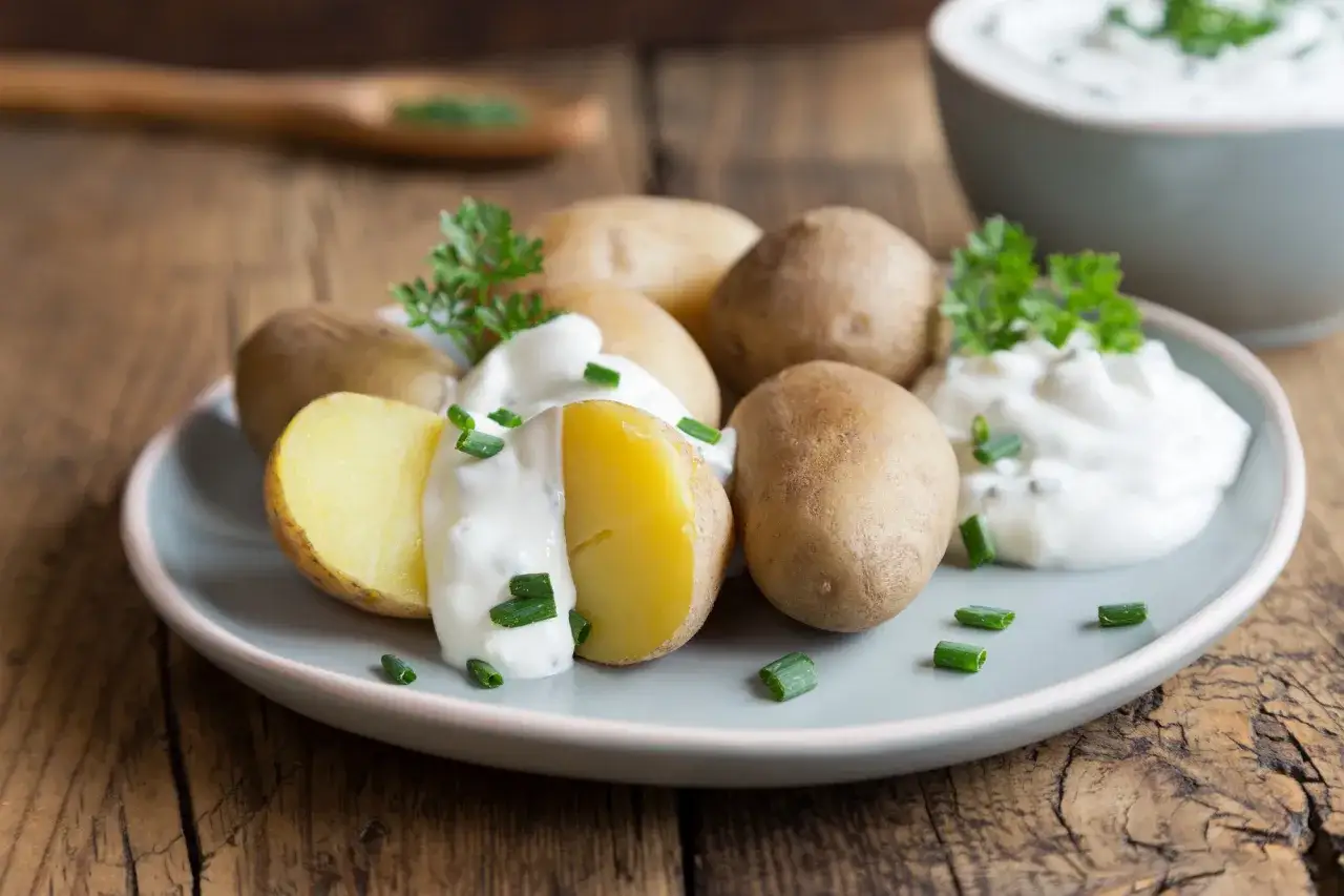 Kleine, gekochte Kartoffeln mit cremigem Quark und frischen Kräutern, garniert mit Schnittlauch. Ein klassisches Gericht: Kartoffeln mit Quark.