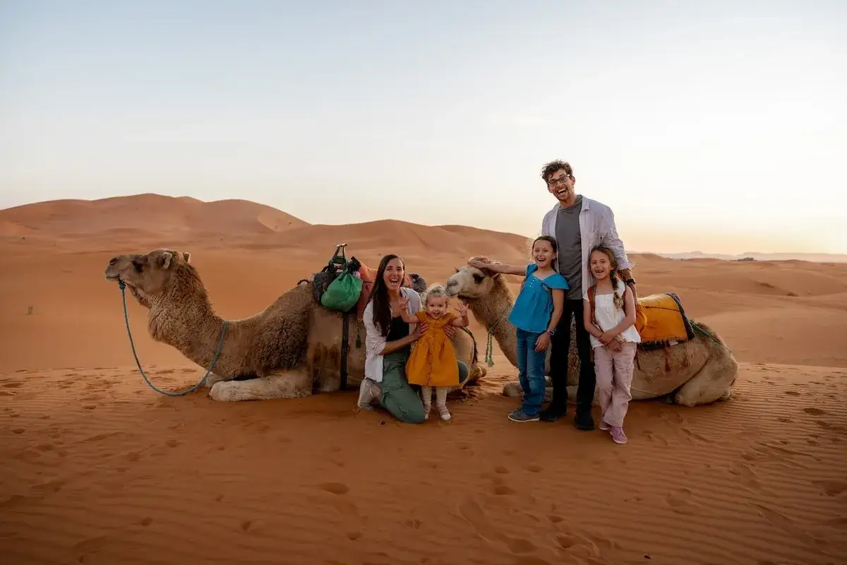 Famille joyeuse profitant d'une balade à dos de chameau dans le désert, une belle expérience pour la saison Maroc.