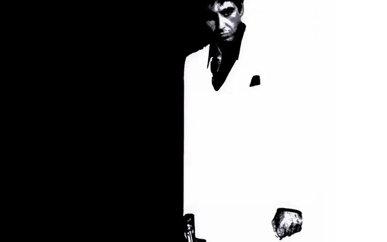 Tony Montana w białym garniturze, zdeterminowany, jakby mówił 