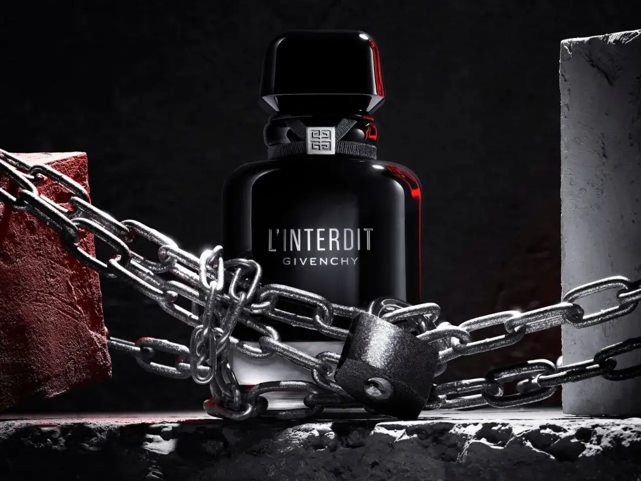 L'Interdit Intense Givenchy, zamknięty w łańcuchach i kłódce, symbolizuje zakazaną, intensywną esencję.