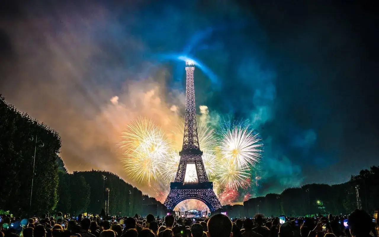 Espectacular espect&aacute;culo de fuegos artificiales ilumina la Torre Eiffel, celebrando porque se celebra el 14 de julio en Francia. Multitud observa.